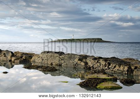Pladda lighthouse with rocky coastline reflections Isle of Arran Scotland