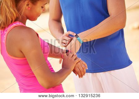 Young people doing sport activities friends running using fitband watch man and woman jogging on the street. Concept of leisure health recreation fitness exercise training