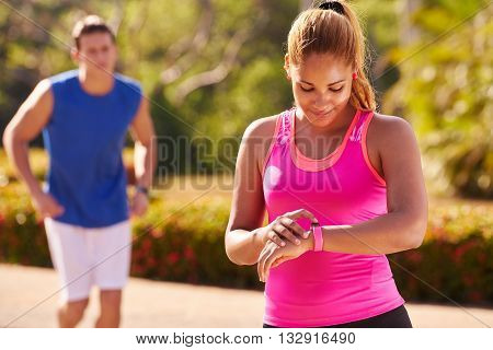 Young people doing sport activities girl and male friend running using fit watch man and woman jogging on the street. Concept of leisure health recreation fitness exercising training workout