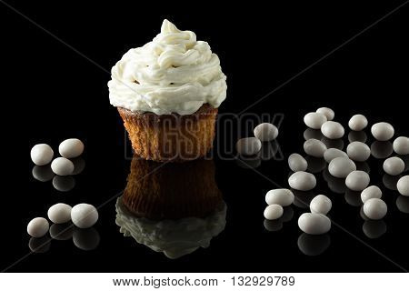 one white muffin on black with reflection