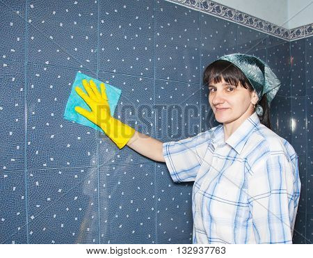 young smiling woman washes a tile in the bathroom