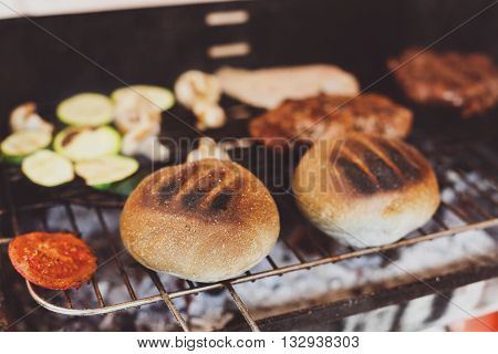 Barbecue grill outdoors. Cookout american bbq food. Big burger roasted buns, pork and beef steak meat, mushrooms, tomato. Street food, fast food.