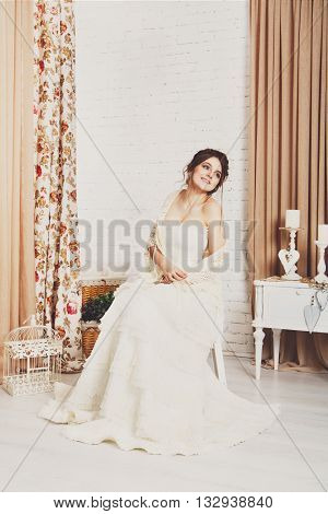 Wedding dress fashion. Beautiful young bride in vintage crochet shawl, shabby chic champagne color wedding dress. Rustic wedding dress at model, in decorated interior, studio shot, high key.
