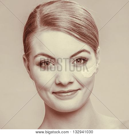 Beauty treatment. Woman applying moisturizing cream skin care product on face studio shot filtered photo