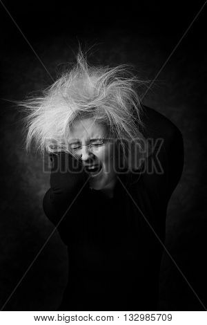 Sexy young woman putting hands in her disheveled hair. Sexy look in black and white portrait. Screaming woman with messy hair.