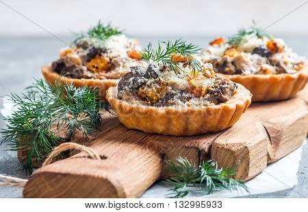 Homemade savory autumn tarts with fresh seasonal mushrooms in a crisp pastry base on gray background