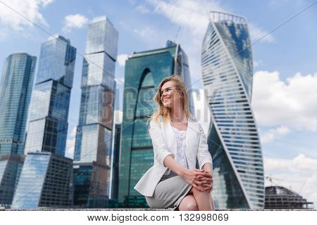 Young woman sitting against office buidings. Coffee break, lunch concept.