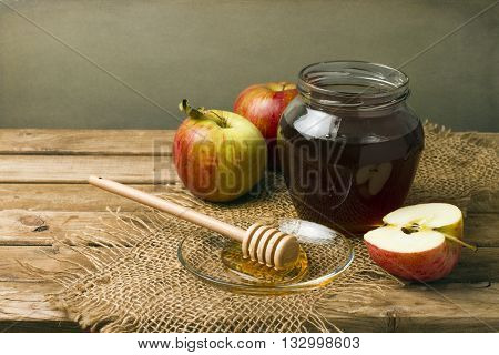 Still life with honey and apples on wooden tabletop
