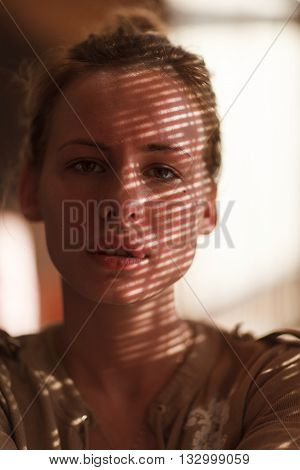 Portrait of young beautiful woman with striped shadow on face.