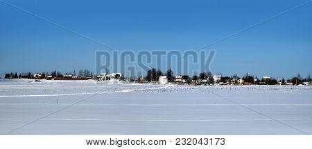 Beautiful Rural Landscape With A Village On Skyline After Snow Field Under Clear Blue Cloudless Sky 