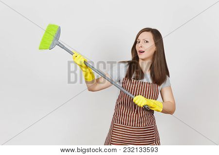 Young Perplexed Housewife In Striped Apron, Yellow Gloves Isolated On White Background. Fun Housekee