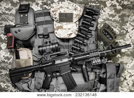 Photo Of A Tactical Vest, Rifle, Gun, Hat With American Flag Badge And Cartrige Belt Laying On Camou