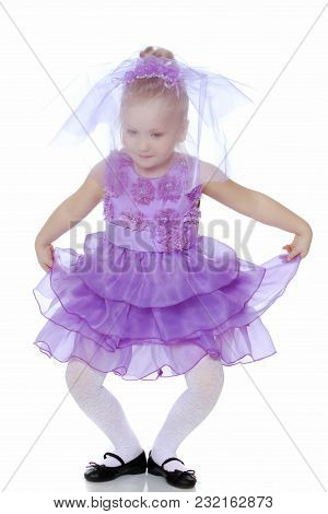 A Sweet Little Round-faced Girl In A Smart Purple Dress. With A Veil Covering His Face.she Makes A C