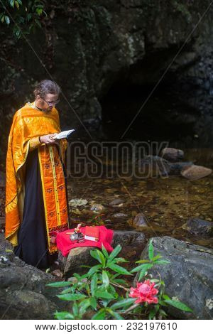 KOH CHANG, THAILAND - MAR 9, 2018: Orthodox priest during sacrament of spiritual birth - Baptism. There are currently 10 Orthodox parishes in Thailand, Orthodoxy is practiced by 0.002% of population.