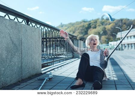 Unpleasant Accident. Frightened Elderly Woman With A Pair Of Crutches Falling To The Ground Unexpect