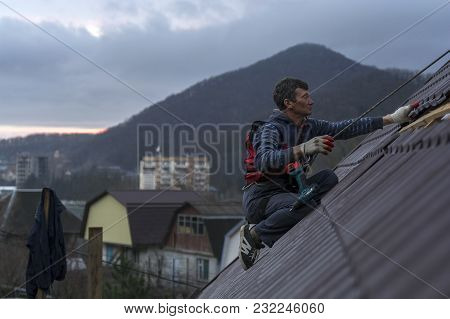 Roofer Assembles Sheet Metal On The Roof. Roofers On The Roof.