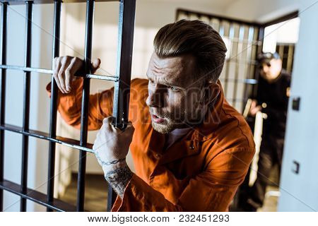View Of Scared Prisoner Leaning On Prison Bars