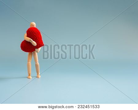 Wooden Puppet Standing And Holding A Red Heart On The Blue Screen Background. Wooden Puppet Holding 