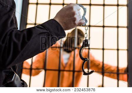 Cropped Image Of Prison Guard Showing Handcuffs To African American Prisoner