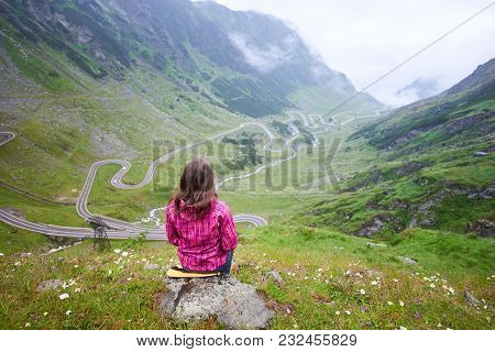 Young Brunette Female Sitting On Stone And Admiring Spectacular View Of Green Rocks And Meadows And 