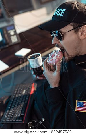 Prison Guard Eating Doughnut And Holding Cup Of Coffee