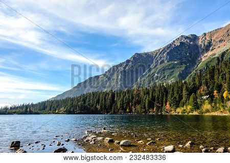 Beautiful Autumn Mountain Landscape With A Lake And A Forest At The Foot Of Rocky Mountains Against 