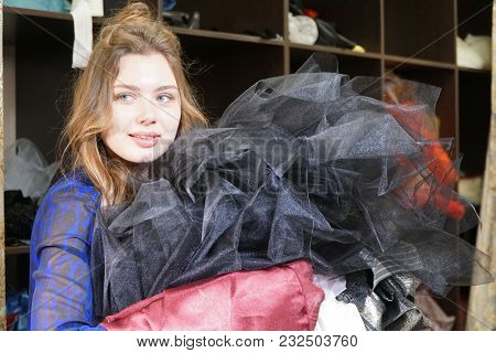 Seamstress, costumier or seller holding a bunch of dresses. Portrait of woman in Studio.