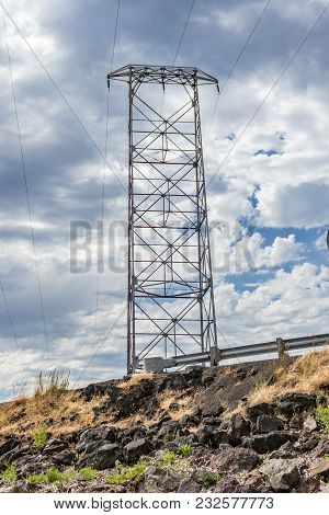 Tall Metal Transformer And Powerlines Over A Grassy Dune Beach