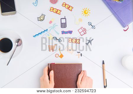 Top View Croped Female Hands Holding Closed Personal Organizer And Colourful Icons Of Actions On Wor