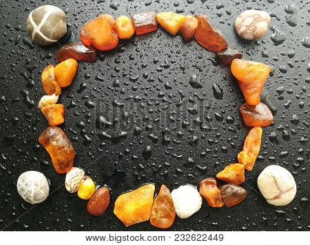Frame Made Of Natural Amber On A Dark Background With Rain Drops.