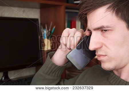 Young Guy Talking On A Black Smartphone With A Smile