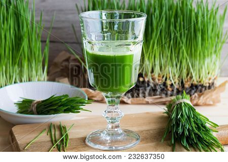 A Glass Of Wheatgrass Juice With Freshly Harvested Wheatgrass On A Wooden Table