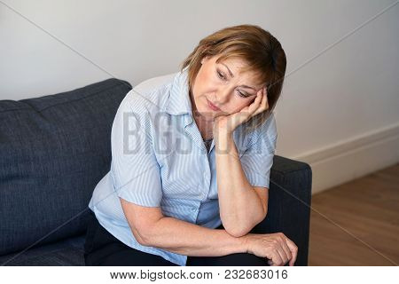 Loss Of A Loved One. Sadly Depressed Elderly Woman At Home, Sitting On The Couch. A Very Unhappy Wom