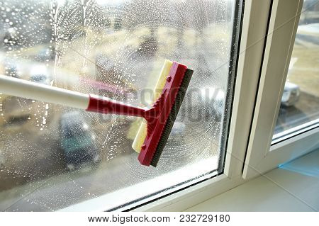 Soapy Window With A Squeegee Cleaning The Glass. Cleaning Windows With A Squeegee.