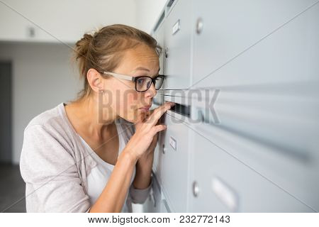 Pretty, young woman checking her mailbox for new letters