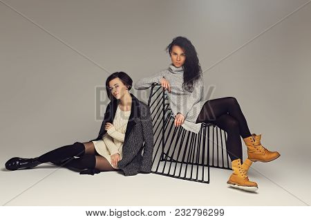 Two Attractive Brunette Women Dressed In Warm Clothes Posing In A Studio.