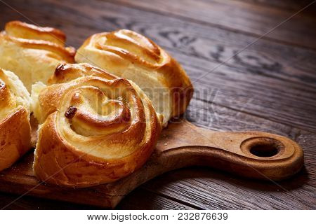 Homemade Rose Buns With Raisins On Wooden Cutting Board Over Rustic Vintage Background, Close-up, Sh