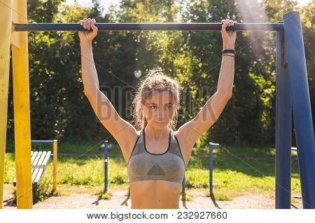Fit Woman Doing Pull-ups. Young Athletic Fitness Woman Working Out At Outdoor Gym Doing Pull Ups At 