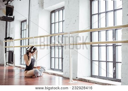 Young girl listen to music on headhones in dance studio