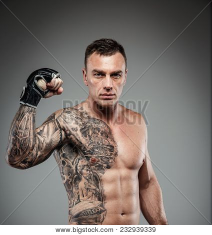 Muscular Tattooed Fighter Against Grey Background. Studio Shot