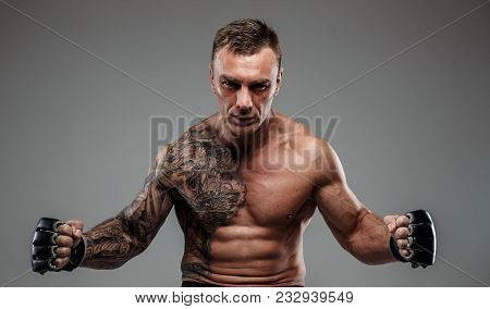 Muscular Tattooed Fighter Against Grey Background. Studio Shot