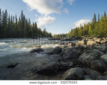 Beautiful Northern Landscape With Long Exposure Water Stream Of River Kamajokk, Boulders And Spruce 