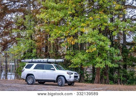 MIller City, IL, USA - October 25, 2019: Toyota 4runner SUV with a stand up paddleboard on roof racks on a shore of Horseshoe Lake in fall scenery.