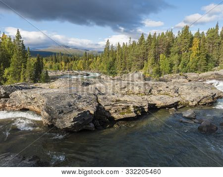 Beautiful Northern Landscape With Wild Glacial River Kamajokk, Boulders And Spruce Tree Forest In Kv
