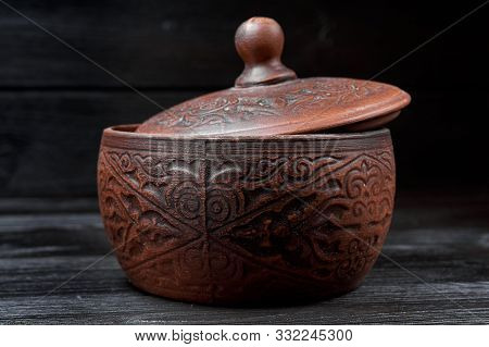 Brown Clay Pan On A Black Wooden Background With Authentic Carvings