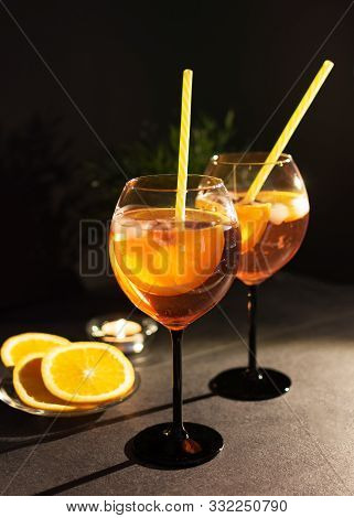 Two Glasses Of Italian Aperol Spritz Cocktail With Orange Slices On Black Background.