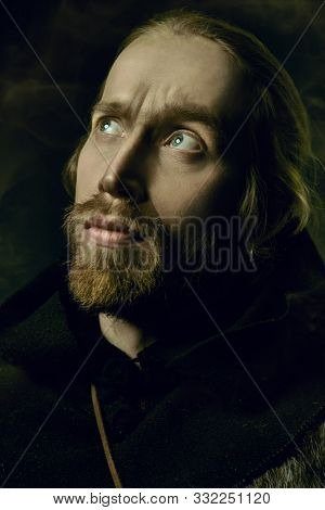 Portrait of a medieval pilgrim in old historical clothes over black background. Historical reenactment. Copy space.