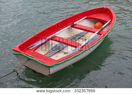 One Small Red Dingey Boat With Oars