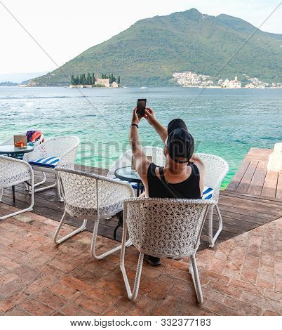 At Perast A Tourist Takes A Photo,looking Across Kotor Bay Towards Sveti Đorđe Island,,montenegro.