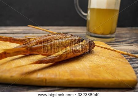 Dried Mullet On A Wooden Board With A Mug Of Beer On The Table. Fish And Seafood Cuisine. Tasty Snac
